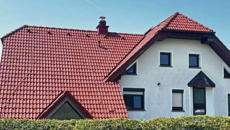 Obnovljena rdeča streha na beli hiši z izrazitim čelnim zatrepom.
