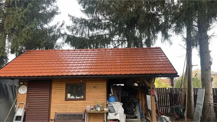 Rdeča streha lesenega vrtnega objekta po čiščenju in barvanju.